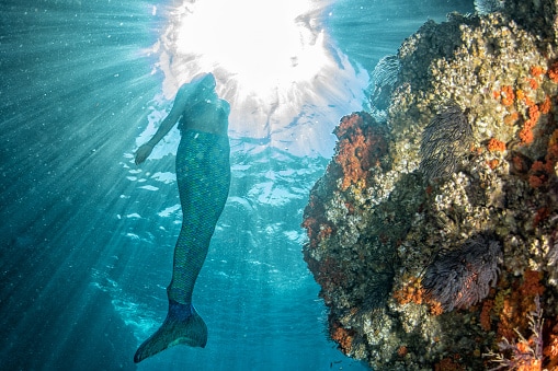 Sirena che nuota sott'acqua nel mare blu profondo