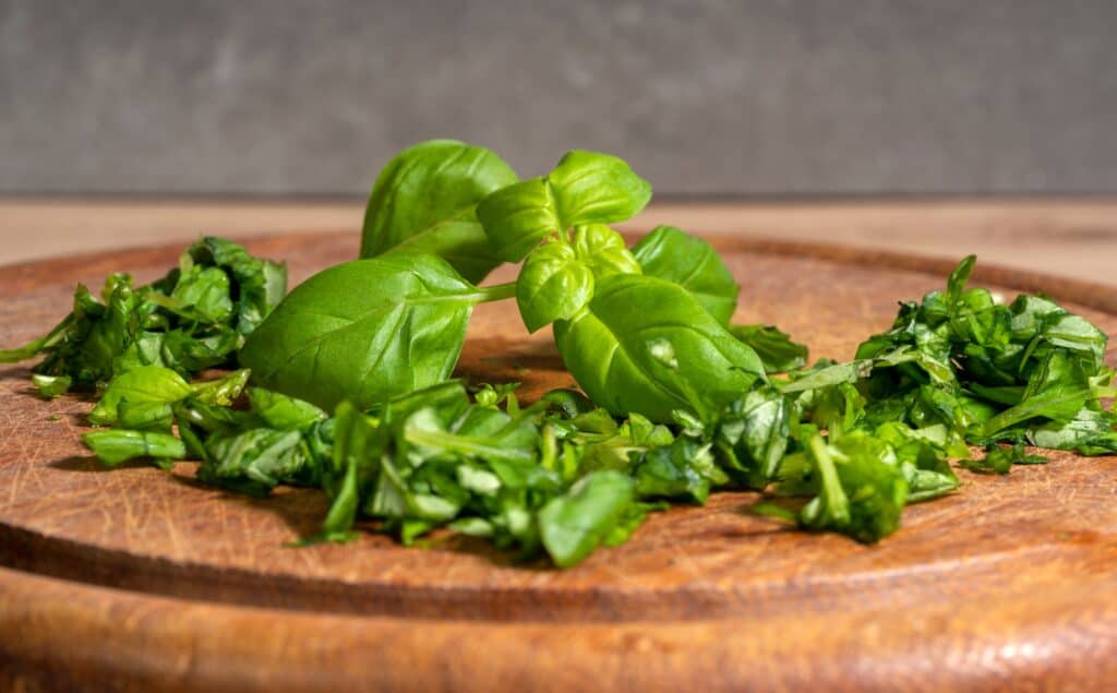 Basilico dolce tritato sul tagliere di legno