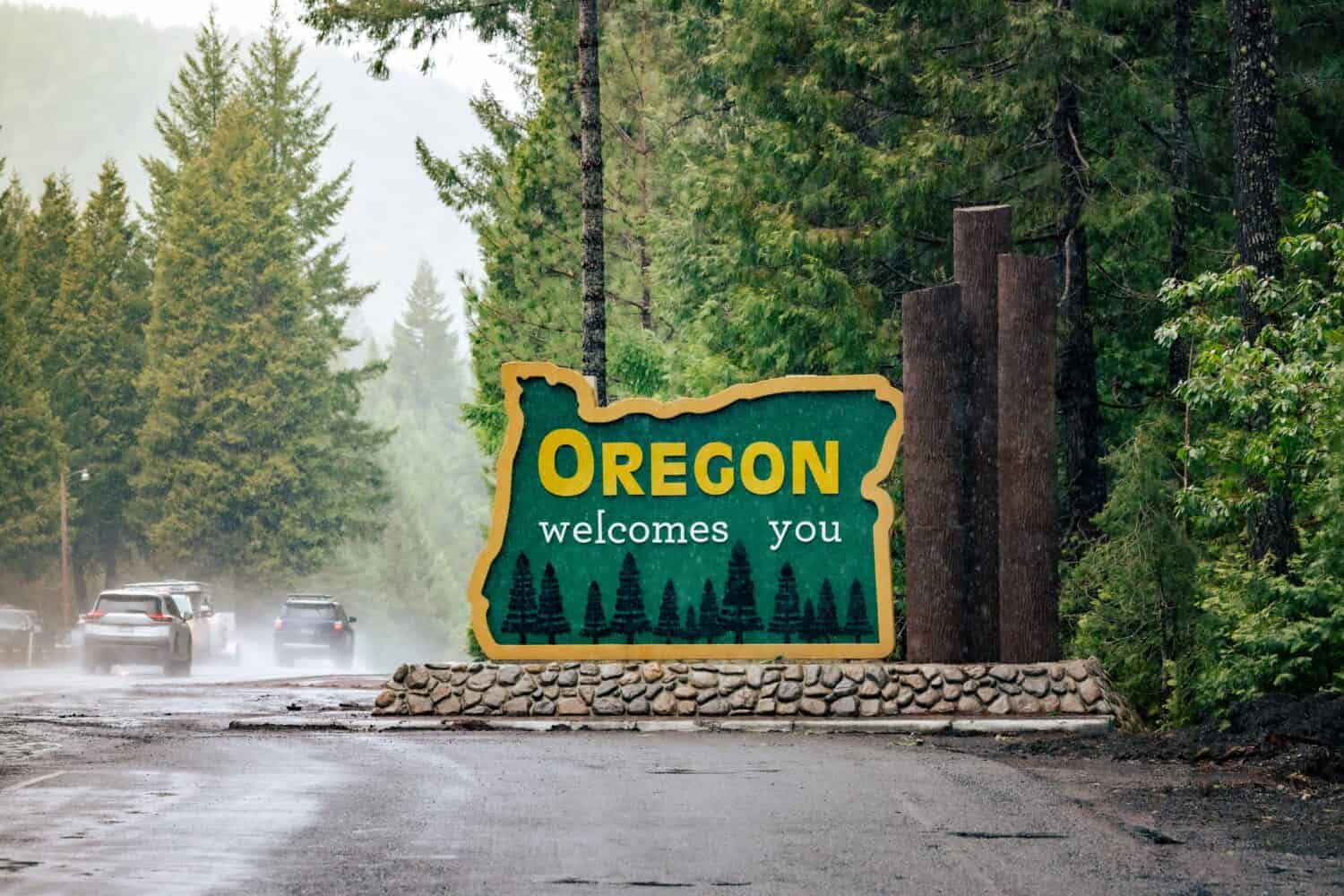 L'Oregon ti dà il benvenuto firmando al confine di stato.  US-HWY 199 Redwood Highway sotto la pioggia.