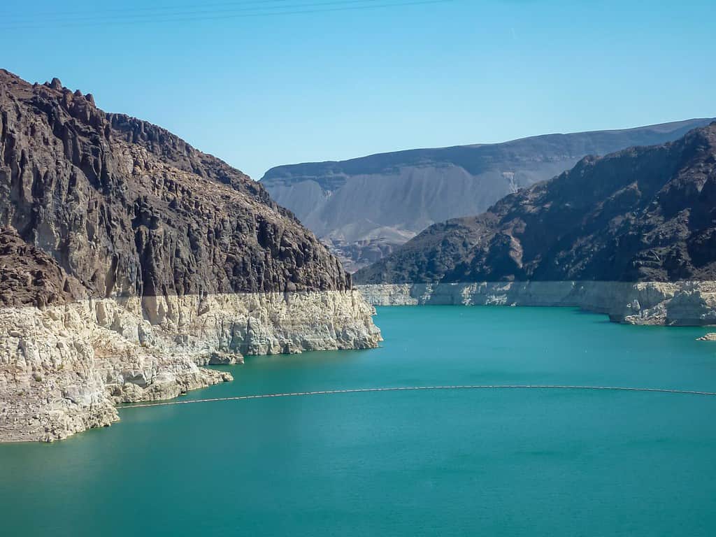 La diga di Hoover guardando verso il lago Mead dal Mike O'Callaghan–Pat Tillman Memorial Bridge, Nevada Arizona State Line, USA.  Acqua turchese blu circondata da lussureggianti catene montuose secche