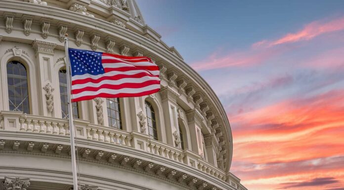 Vista della cupola rotonda del Campidoglio degli Stati Uniti a Washington DC con la bandiera americana Star Spangled su sfondo colorato cielo al tramonto drammatico