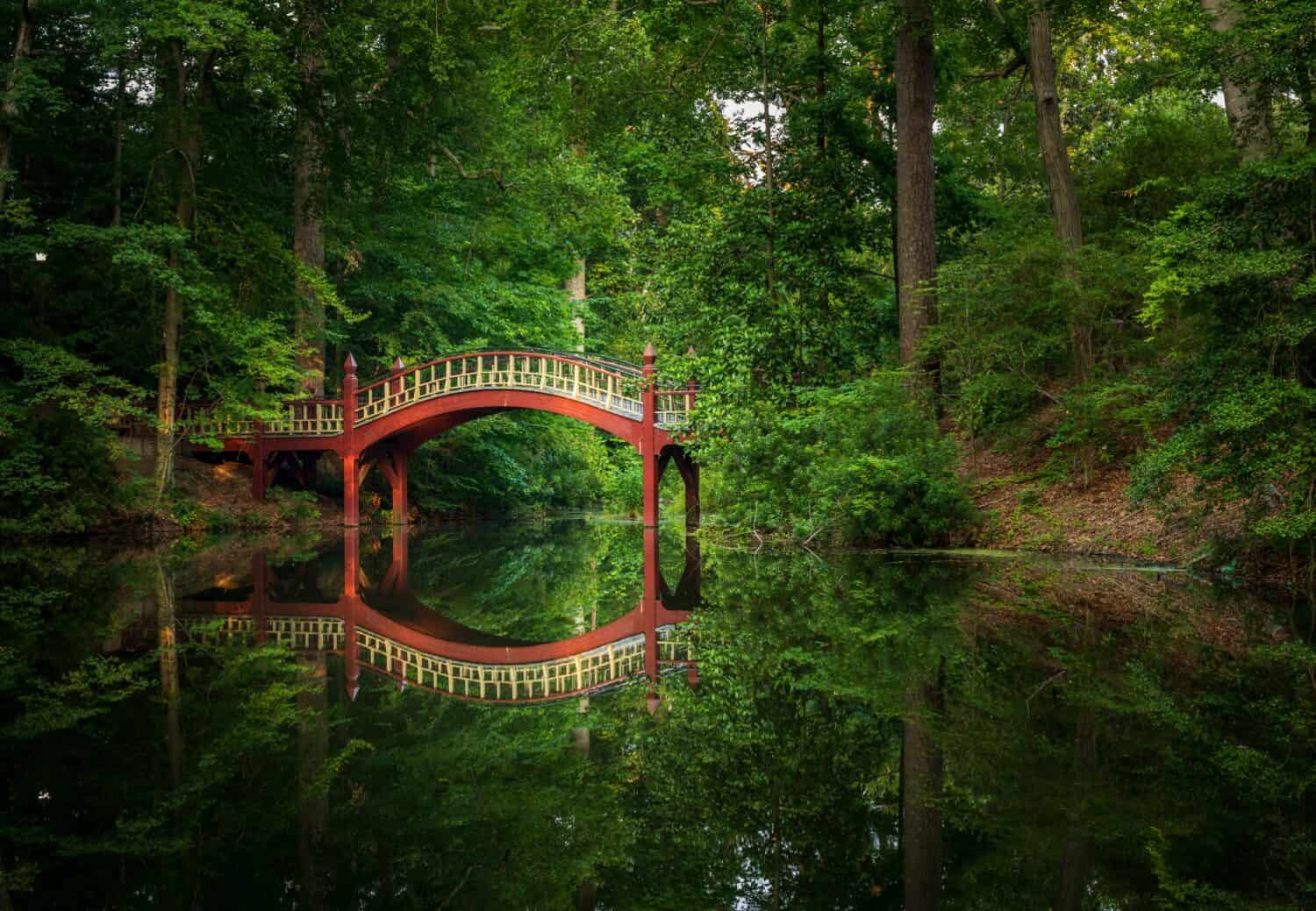 Ponte di legno ornato su un laghetto Crim Dell molto calmo nel campus del William and Mary College di Williamsburg, Virginia