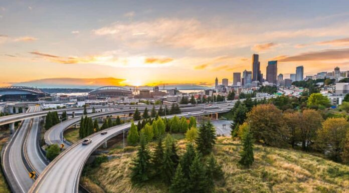 Gli skyline di Seattle e le autostrade interstatali convergono con Elliott Bay e lo sfondo del lungomare al tramonto, Seattle, Washington state, USA.