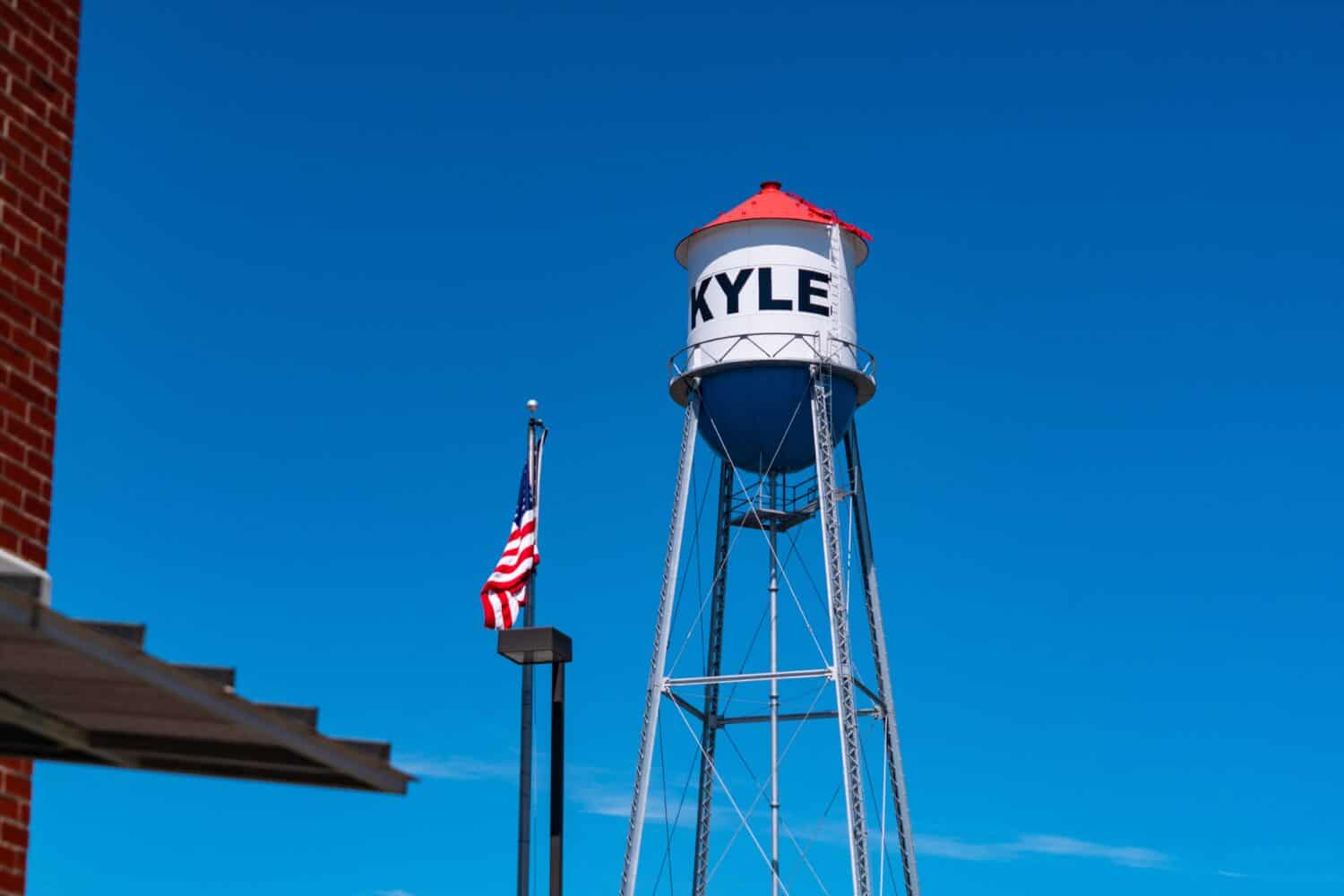 Torre dell'acqua rossa, bianca e blu nella piccola città del Texas con cielo blu nella città del Texas centrale Kyle, Texas, USA con la bandiera americana sull'asta della bandiera