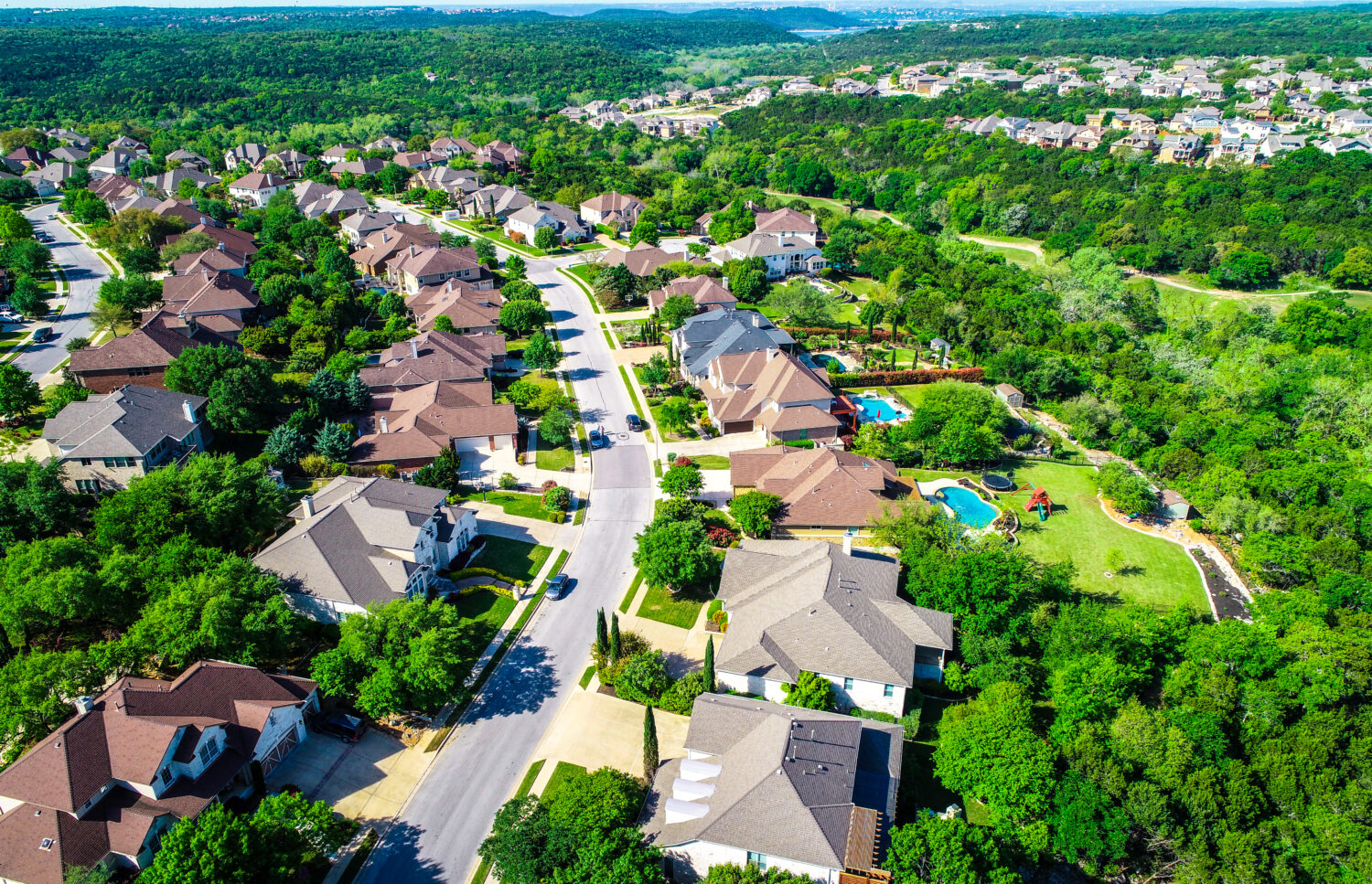 Vista aerea del drone sopra la strada curva con case di lusso del palazzo che conducono al paesaggio verde delle colline Cedar Park Texas Suburb