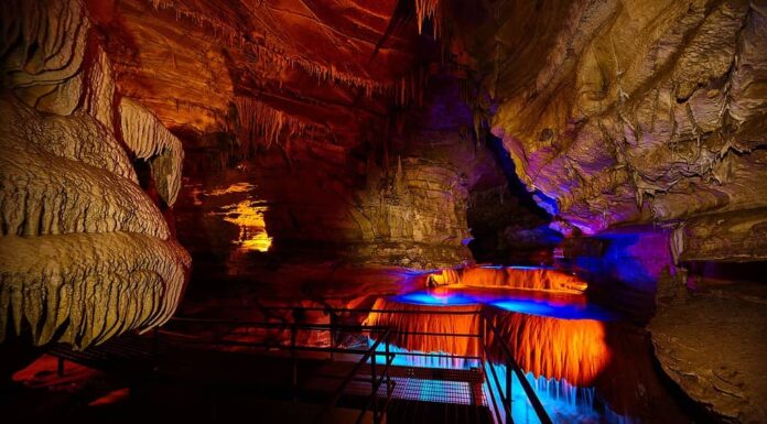 Percorso del tour attraverso la grotta sotterranea dell'Indiana con cascata illuminata da luci blu e arancioni
