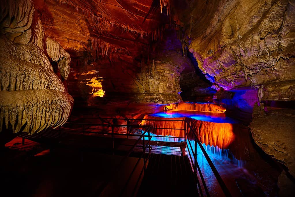 Percorso del tour attraverso la grotta sotterranea dell'Indiana con cascata illuminata da luci blu e arancioni