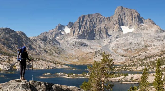 Una donna escursionista si erge in alto sopra il lago Garnett nella Sierra Nevada.  Il deserto di Ansel Adams, Sierra Nevada, California