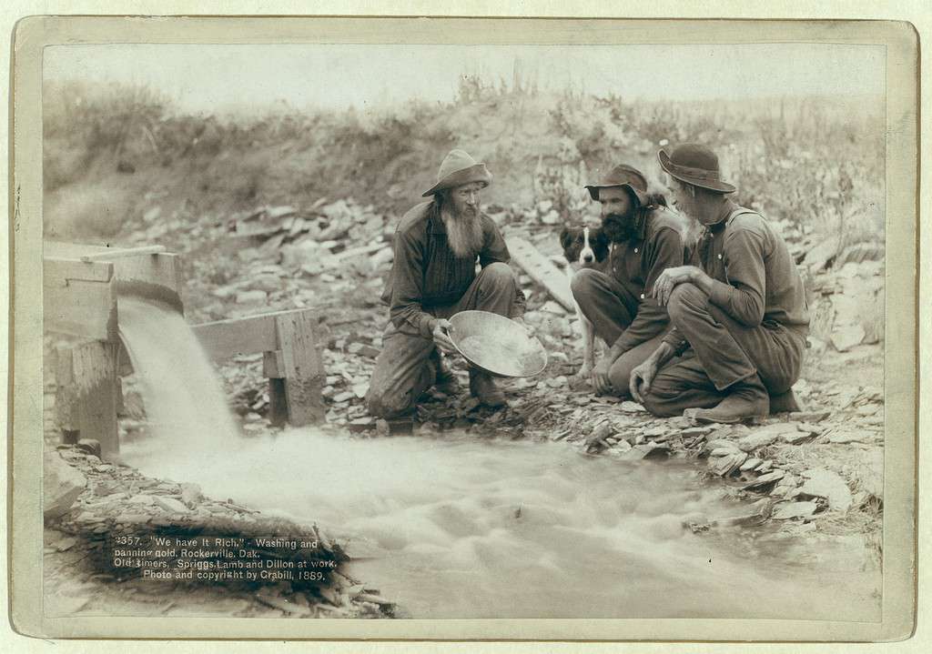 Immagine di cercatori d'oro che lavano e setacciano l'oro.