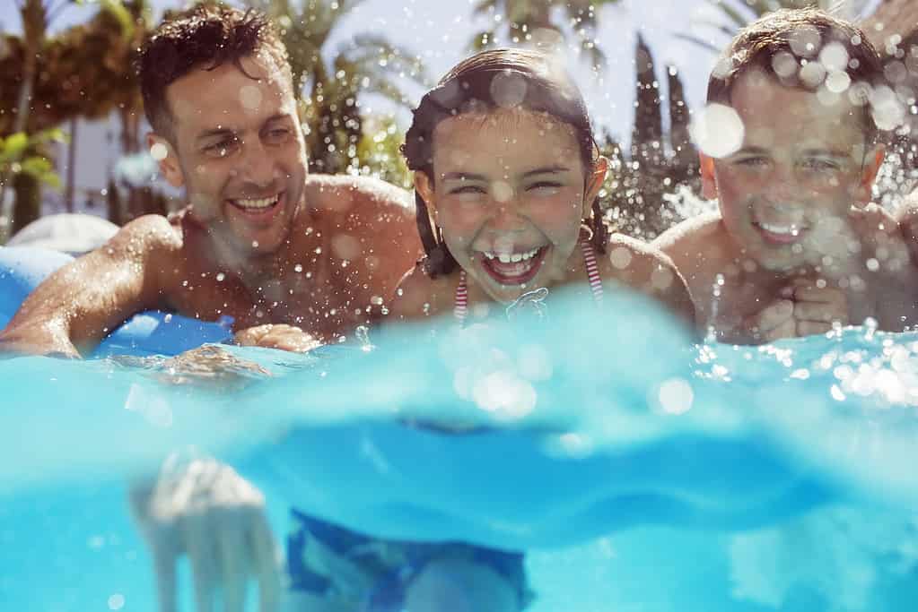 Due bambini e un adulto che nuotano nell'acqua