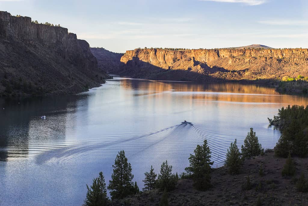 Barca a motore sul bellissimo lago al tramonto.  Lago Billy Chinook nell'Oregon, USA, il parco statale di Cove Palisades