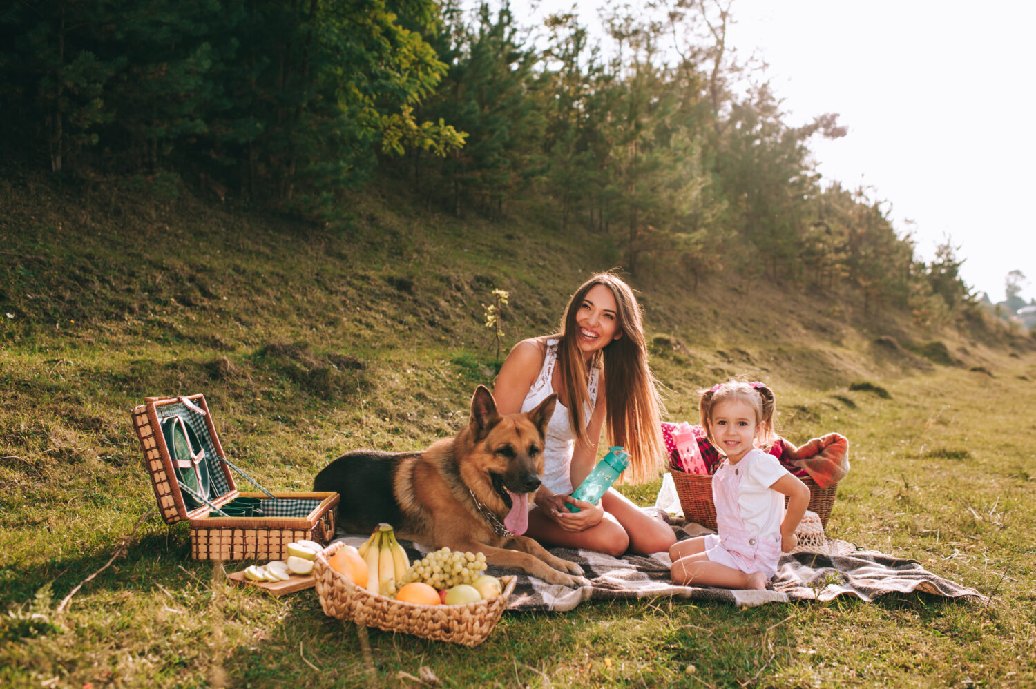 madre e figlia ad un picnic con un cane da pastore tedesco