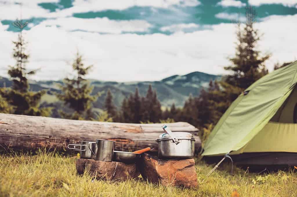 Cucinare la colazione su un falò in un campo estivo.