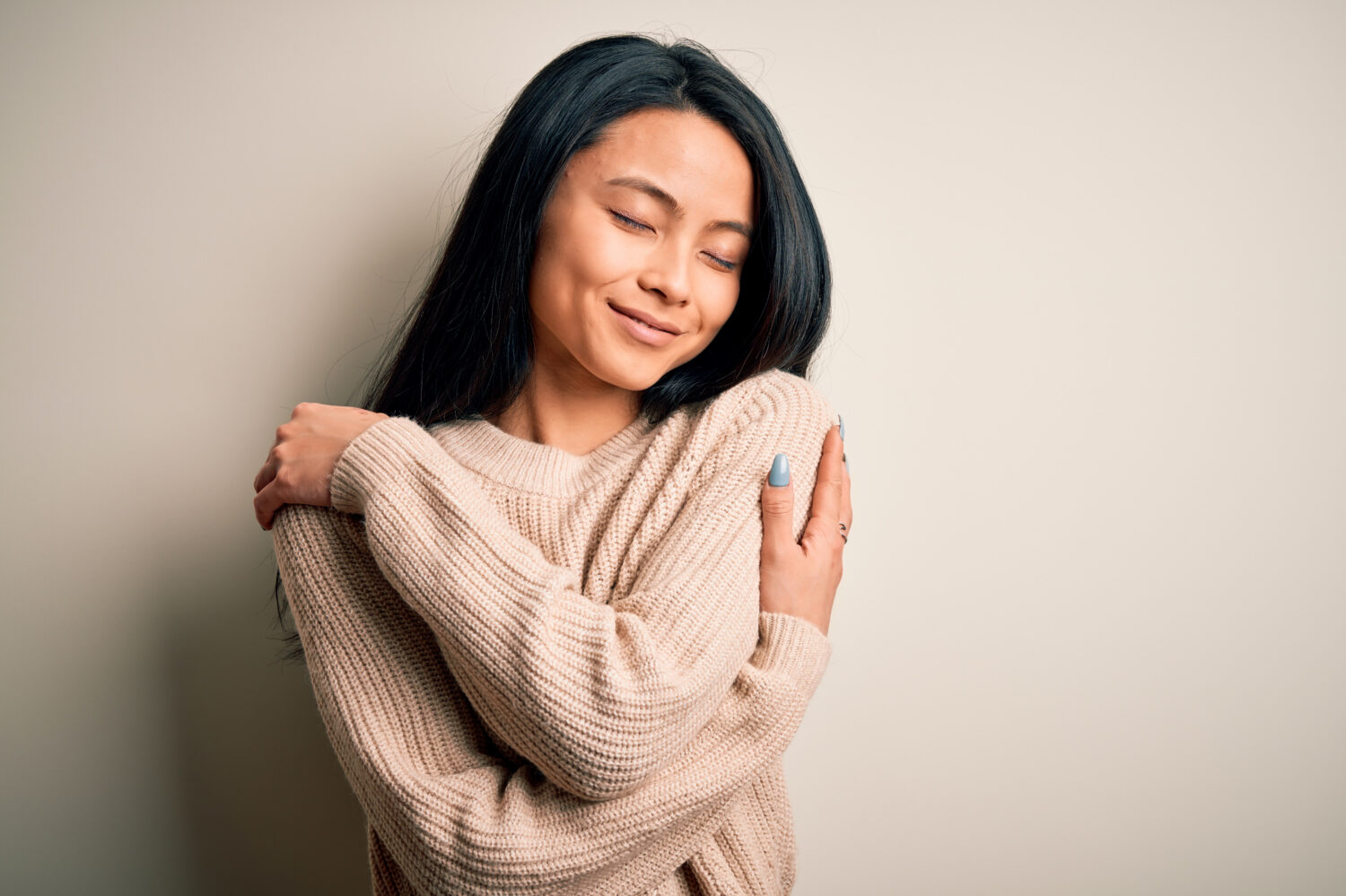 Giovane bella donna cinese che indossa un maglione casual su sfondo bianco isolato Abbracciandosi felice e positivo, sorridendo fiducioso.  Amore per se stessi e cura di sé