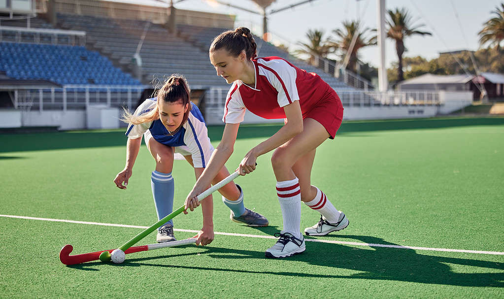 Due concorrenti si contendono la palla durante una partita di hockey su prato.