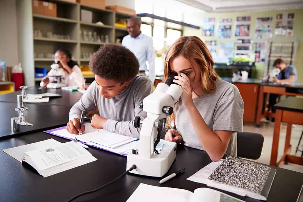 Studenti delle scuole superiori che guardano attraverso il microscopio nella classe di biologia