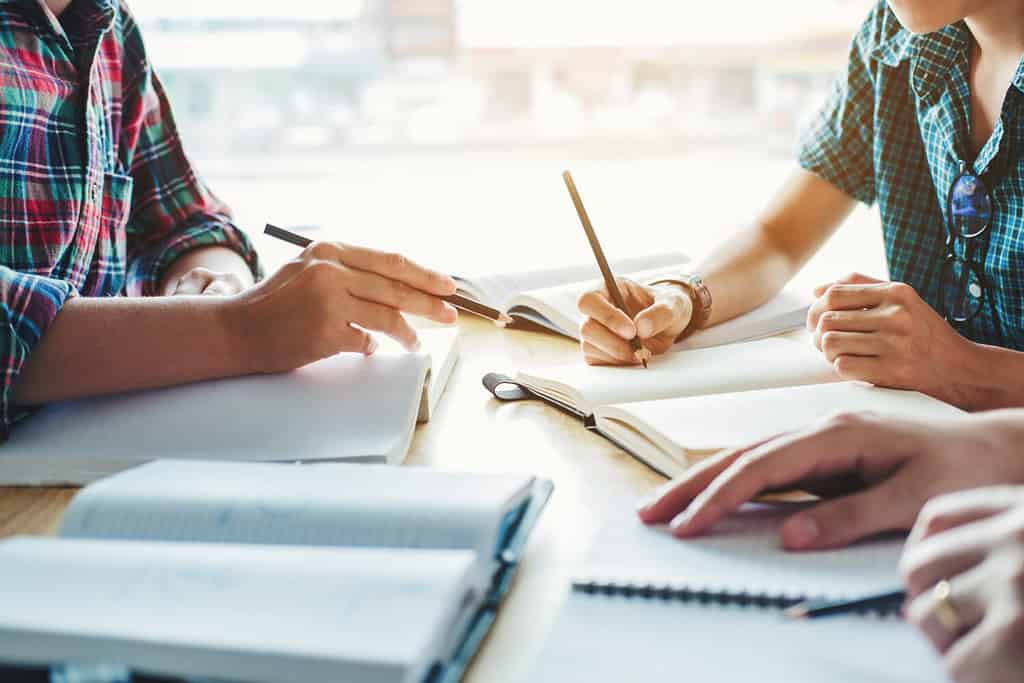 Studenti delle scuole superiori o universitari che studiano e leggono insieme concetti di educazione in biblioteca