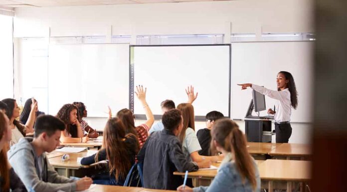 Insegnante di scuola superiore femminile che fa domande in piedi accanto alla lezione di insegnamento della lavagna interattiva