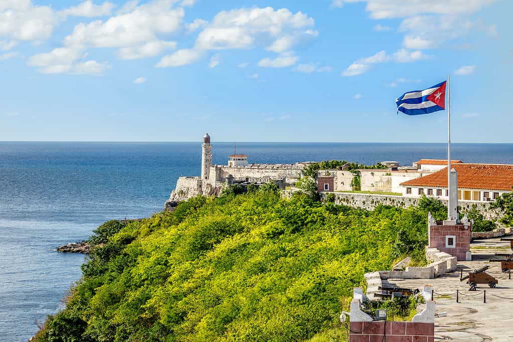 Fortezza spagnola di El Morro con faro, cannoni e bandiera cubana in primo piano, con il mare sullo sfondo, Havana, Cuba