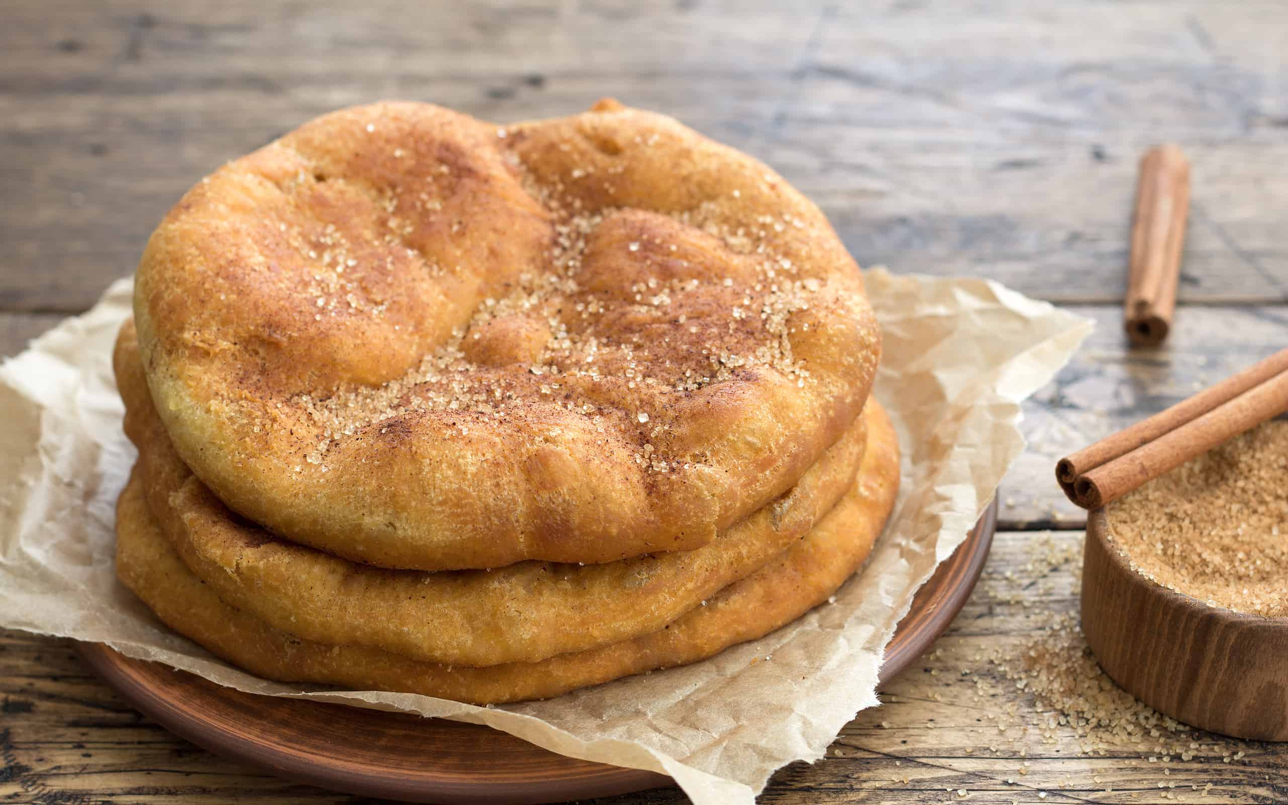 Pane fritto Navajo fatto in casa o orecchie di elefante dolci con zucchero di canna e cannella su tavolo di legno