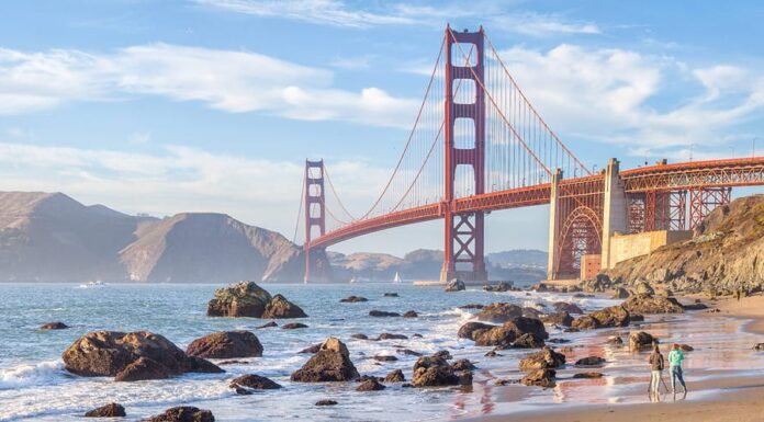 Classica vista panoramica del famoso Golden Gate Bridge visto dalla pittoresca Baker Beach nella splendida luce dorata della sera in una giornata soleggiata con cielo azzurro e nuvole in estate, San Francisco, California, Stati Uniti