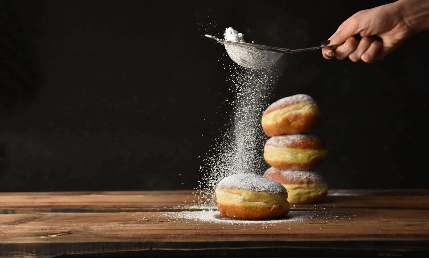 Ciambella europea cosparsa di zucchero a velo su sfondo nero