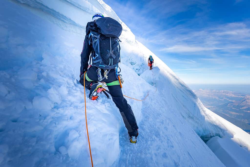 Due alpinisti alpinisti che si arrampicano su una crepa di crepaccio di neve ghiacciata, alpinismo sportivo estremo.  Massiccio del Monte Bianco, turismo di viaggio in Europa.