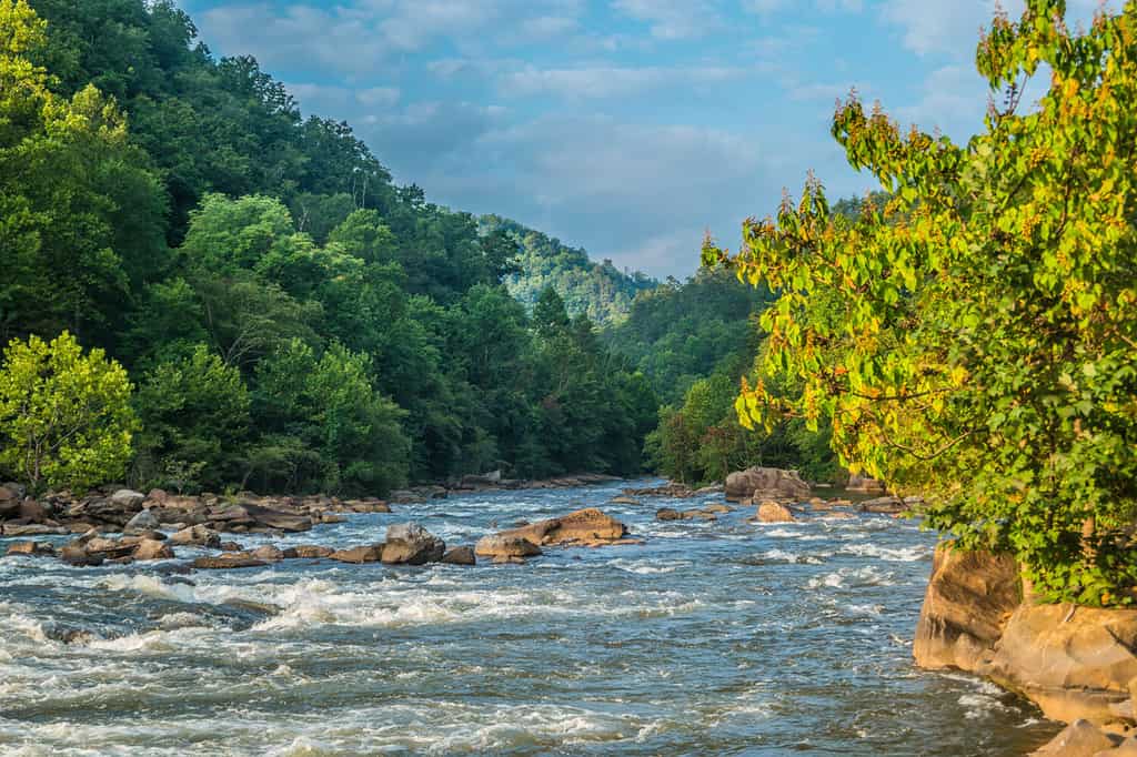 Il fiume Ocoee nel Tennessee con le sue acque bianche che scorre a valle in primo piano con la nebbia nelle montagne sullo sfondo in una luminosa giornata di sole all'inizio dell'autunno