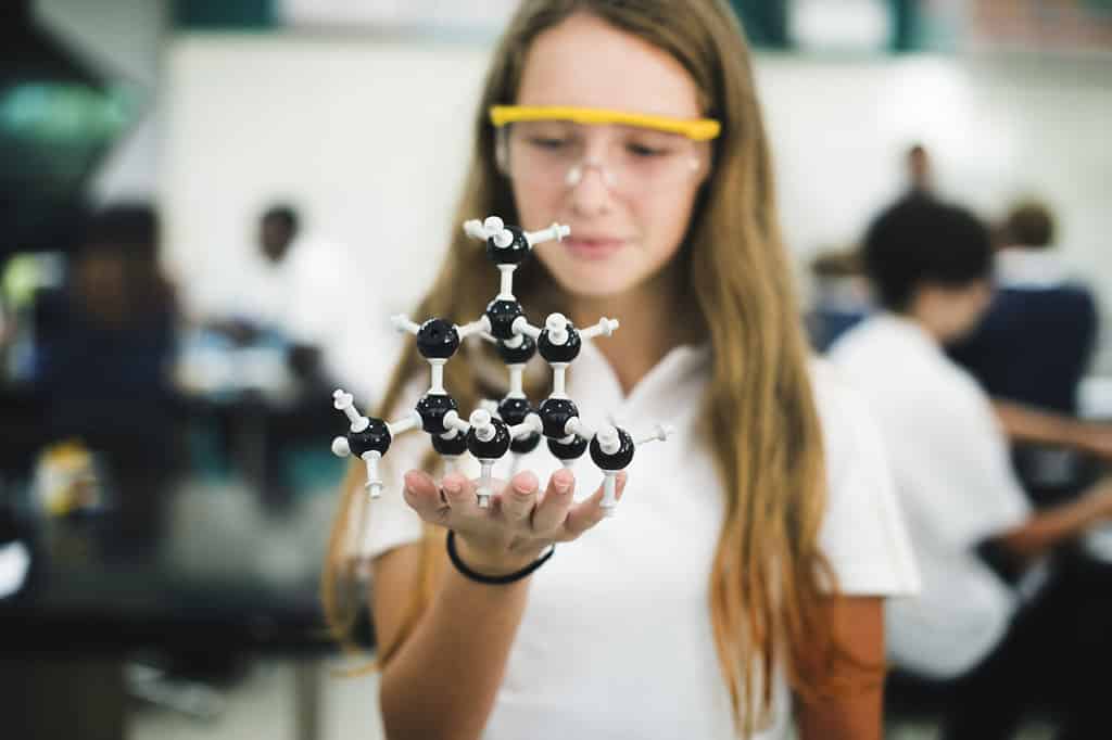 Mano dello studente della scuola superiore che tiene la struttura della molecola nella classe di chimica