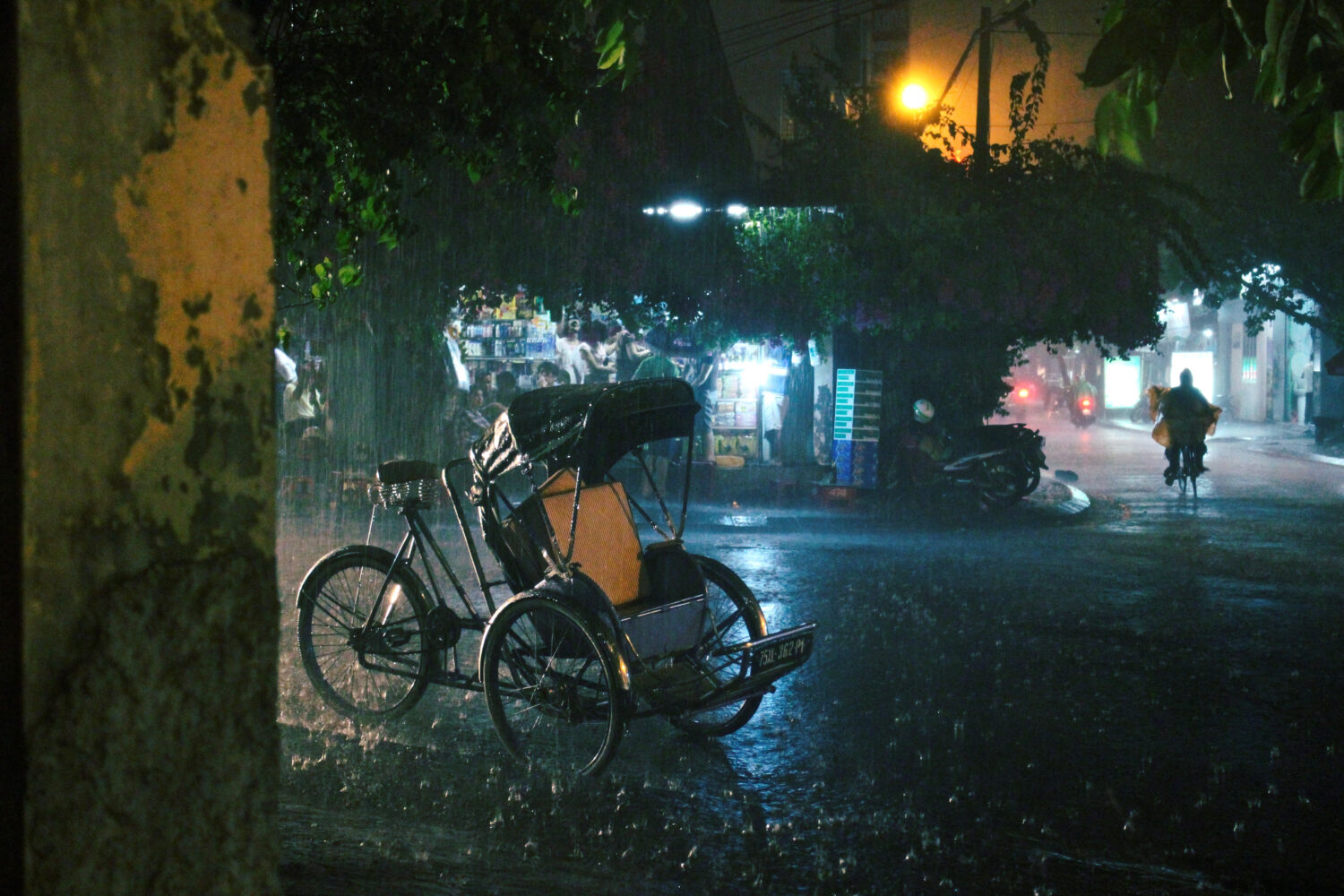 Un ciclo (risciò in bicicletta) parcheggiato sulla strada durante un acquazzone serale di pioggia, Hanoi, Vietnam.