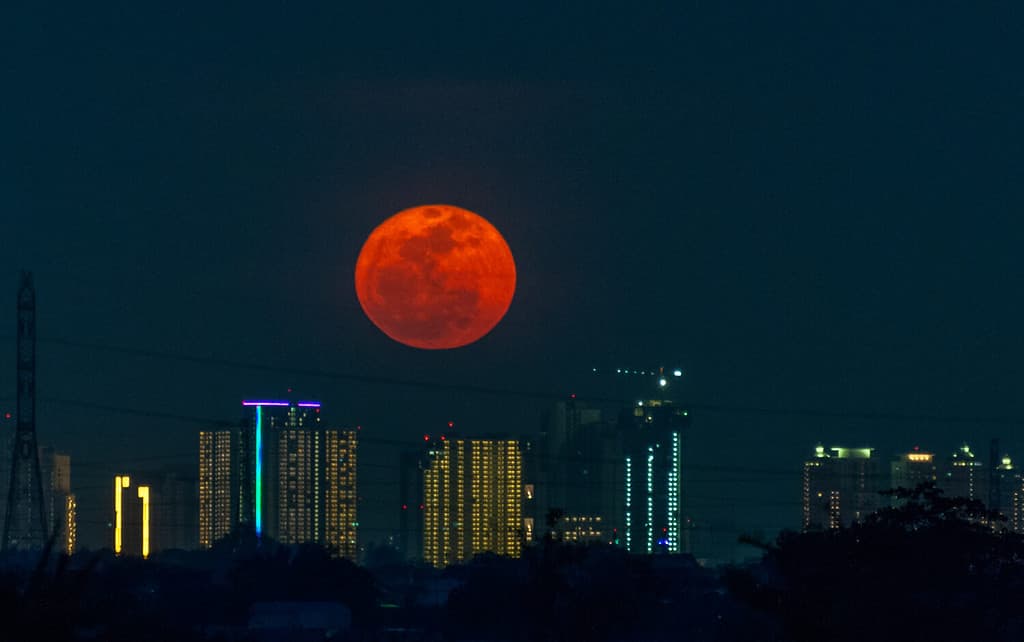 la Luna del Cacciatore sorge sul grattacielo, nel momento in cui la luna piena sorge con tonalità di colore rossastro perché è basso l'orizzonte
