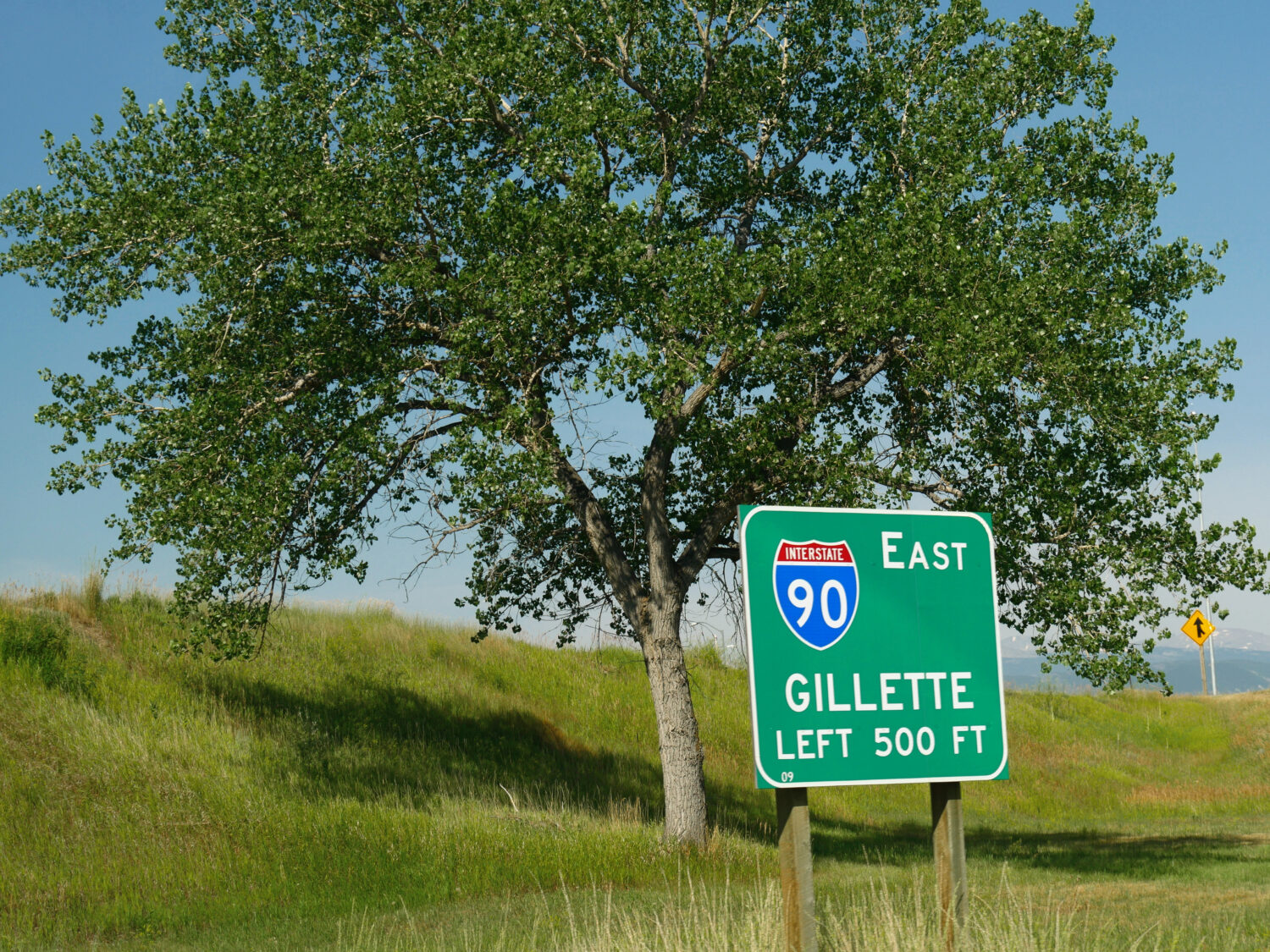 Cartello stradale da un albero all'Interstate 90 con la distanza da Gillette, Wyoming.