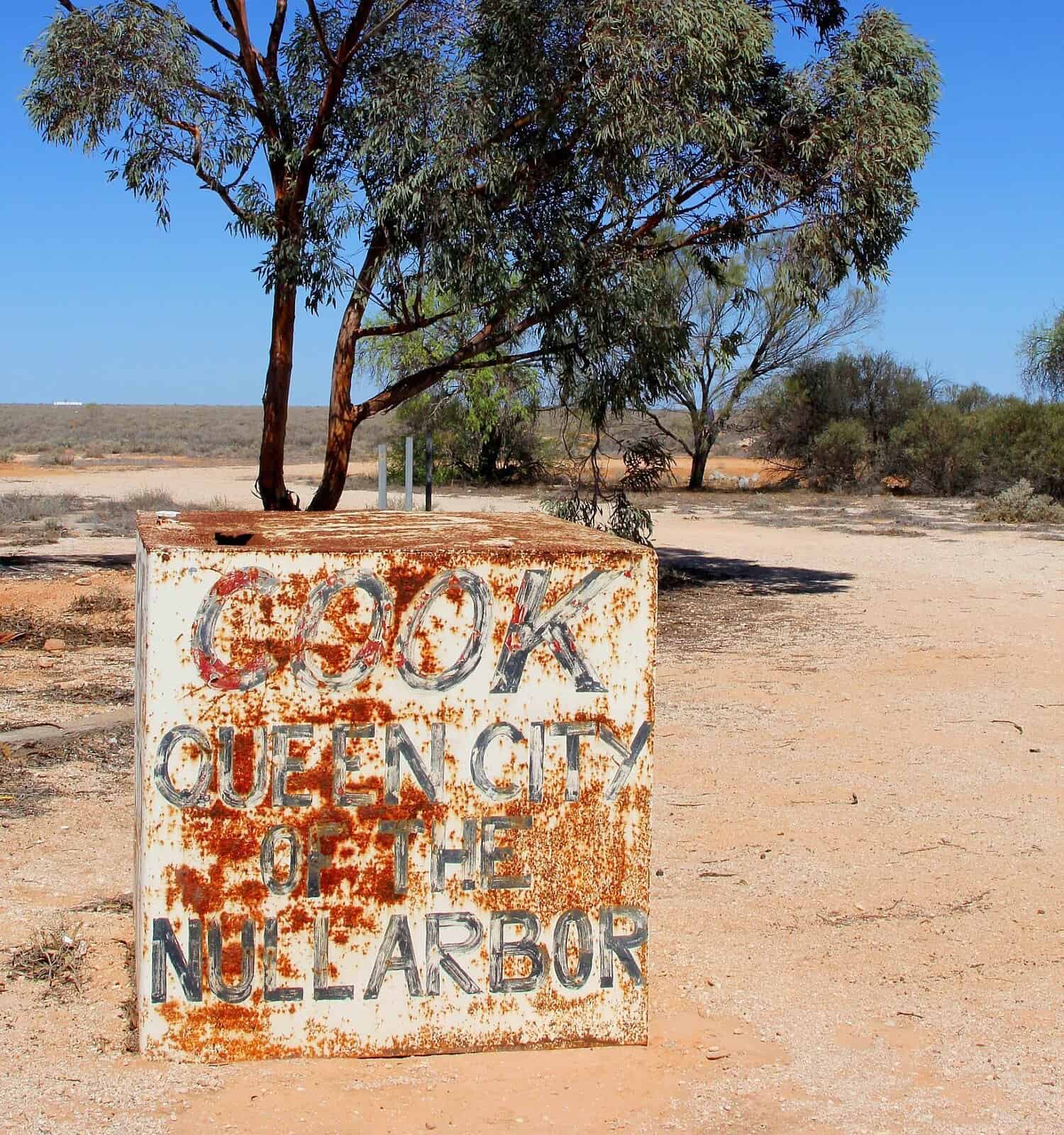 Cartello grungy del villaggio Cook sulla pianura di Nullarbor, Australia.  Il treno dell'Indian Pacific si ferma alla stazione ferroviaria di questa città fantasma dove vivono ancora solo cinque persone. 