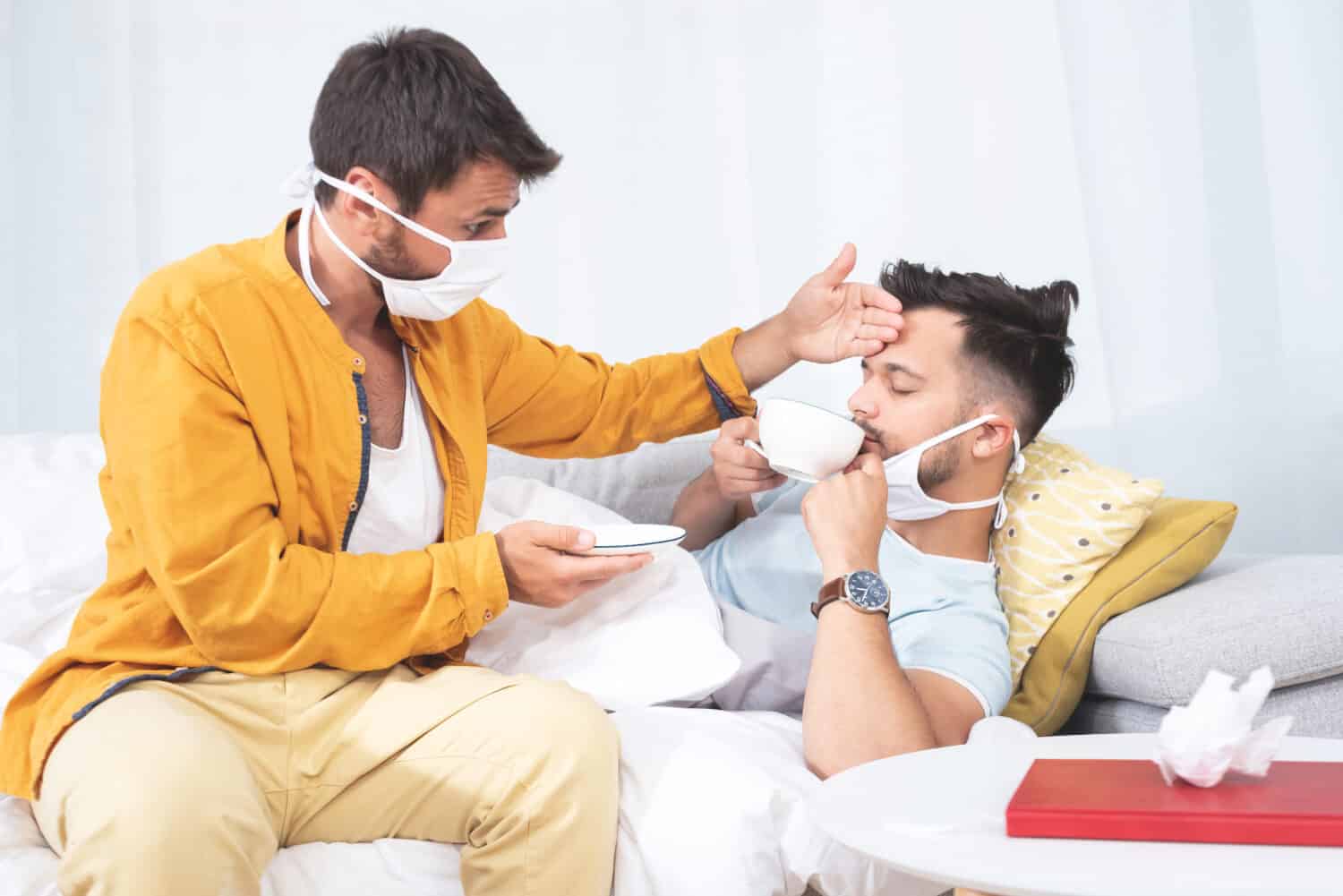 Uomo che serve caffè e controlla la temperatura del partner gay affetto da malattia da virus corona