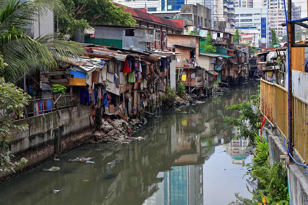 Vista verso N dal ponte di Soler Street alle rive affollate di baracche del canale Estero de San Lazaro del fiume Pasig-Torri Broadview sullo sfondo.  Binondo Chinatown District-Manila-Filippine