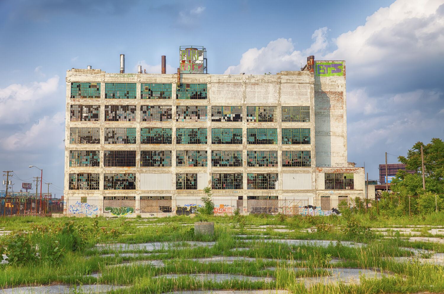 Una vecchia fabbrica nella zona di Highland Park mostra la difficile situazione postindustriale di Detroit con finestre rotte e un parcheggio pieno di erbacce. 