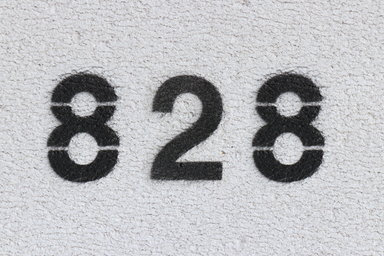 Numero nero 828 sul muro bianco.  Vernice spray.  Numero ottocentoventotto.