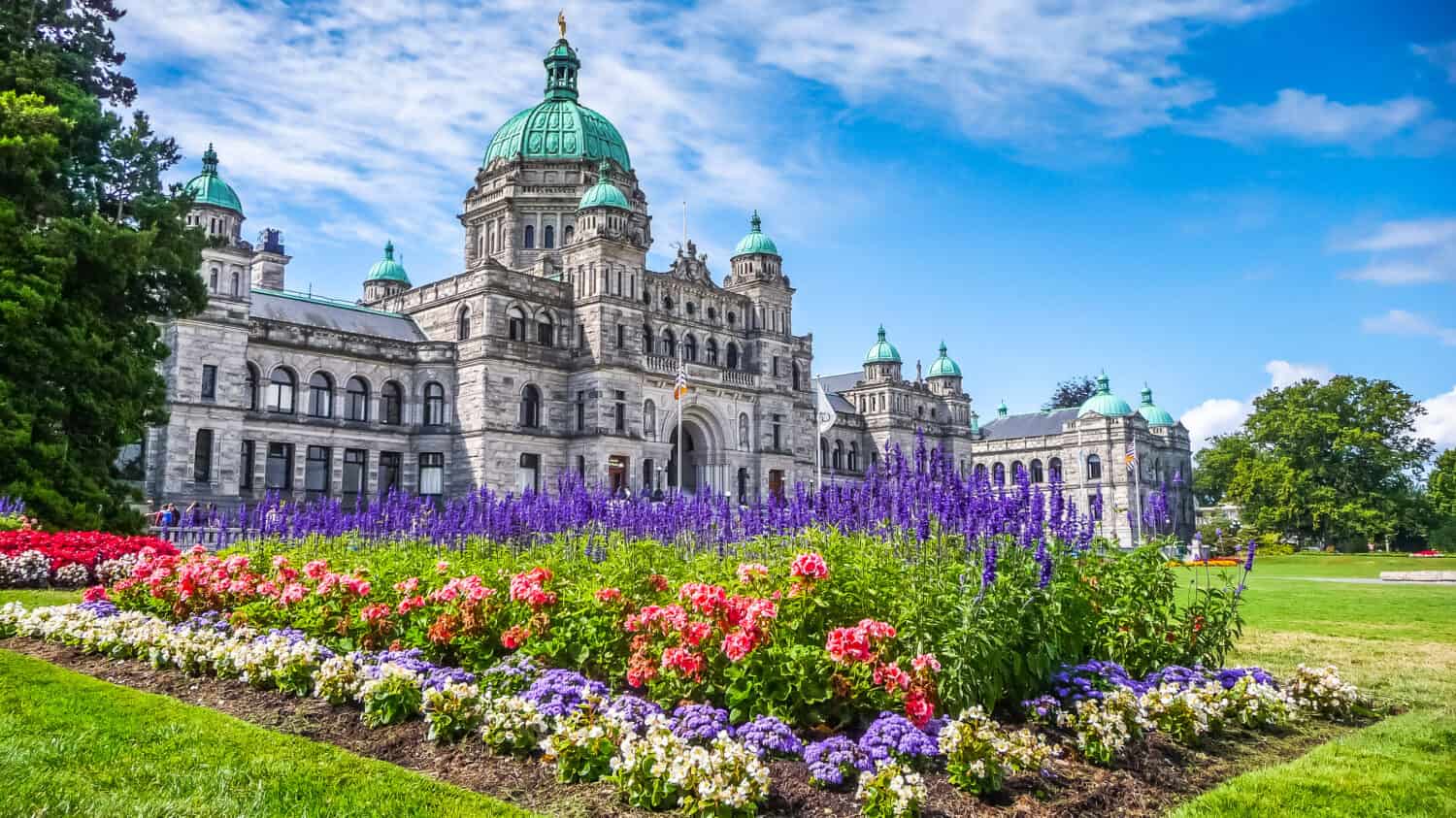 Bellissima vista dello storico edificio del parlamento nel centro di Victoria con fiori colorati in una giornata di sole, Isola di Vancouver, British Columbia, Canada