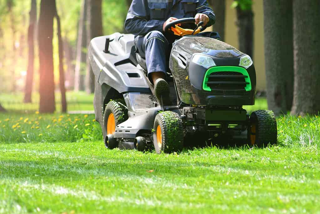 Tosaerba professionale con operaio che taglia l'erba in un giardino