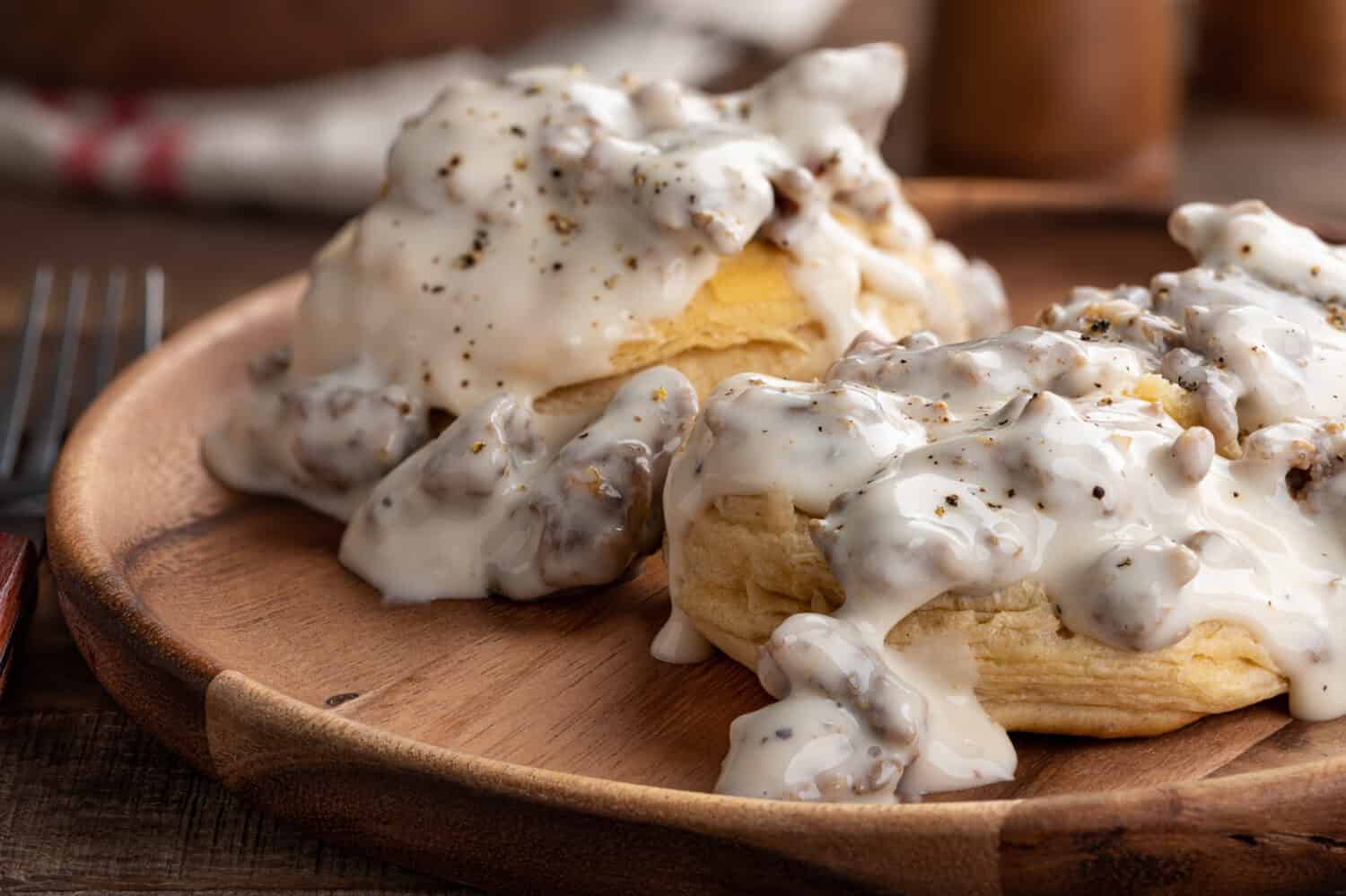 Primo piano di biscotti e sugo cremoso di salsiccia su un piatto di legno 