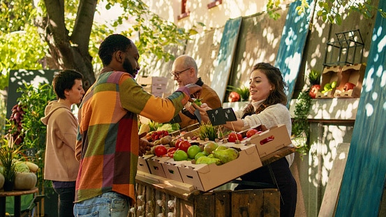 Coltivatrice che offre campioni gratuiti di mele ai clienti per la degustazione di cibo