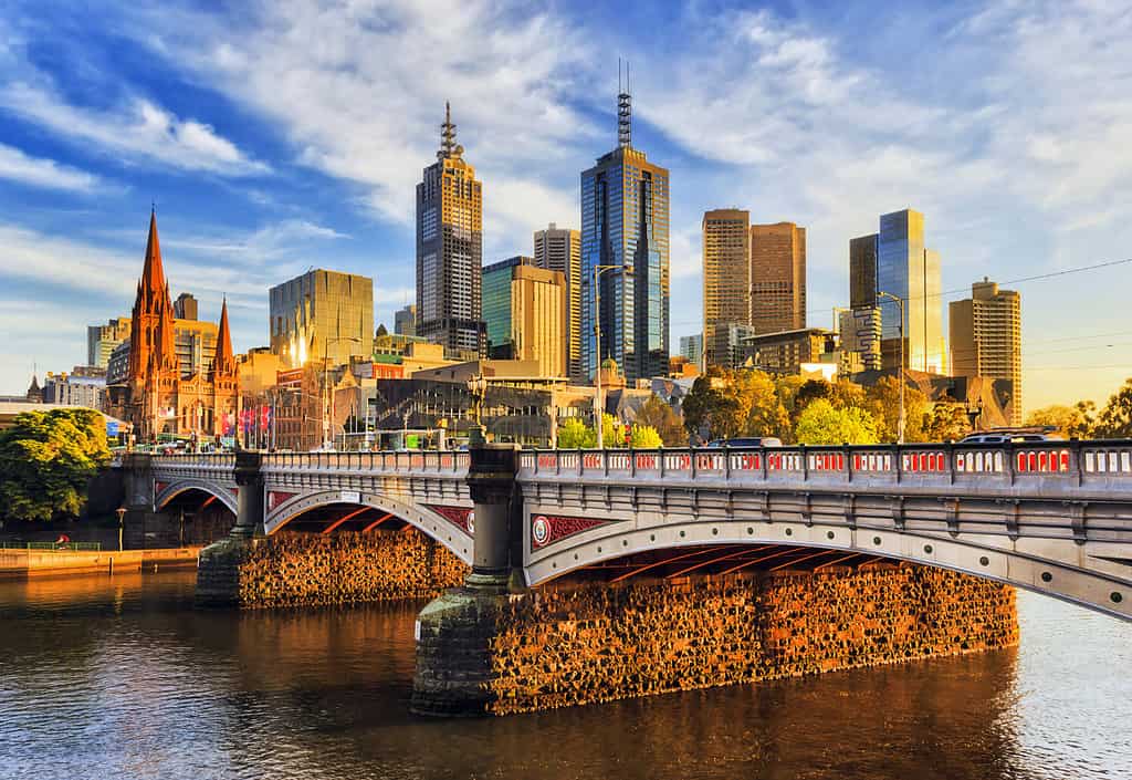 La calda luce mattutina sulle torri alte del CBD di Melbourne sopra il ponte Princes sul fiume Yarra.