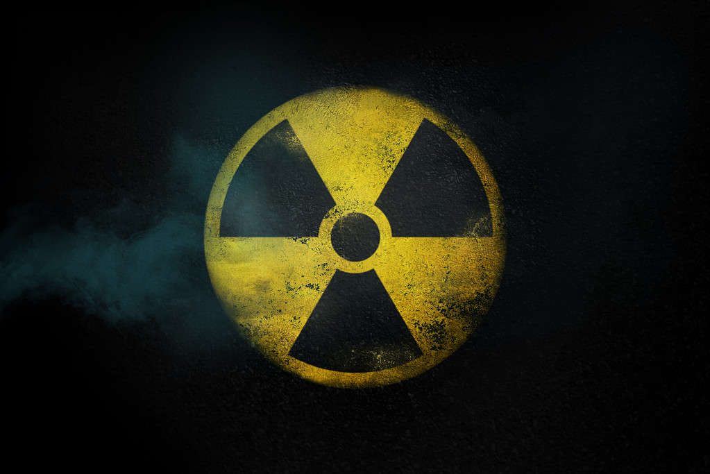 Simbolo giallo rotondo radioattivo dell'energia nucleare sulla struttura dell'asfalto