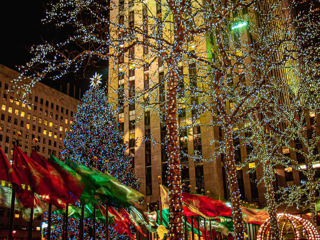 Bandiere natalizie e albero di Natale in una notte ventosa al Rockefeller Center di New York City.