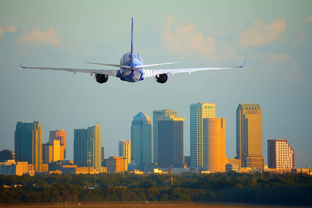 Tampa, Florida, skyline con calda luce del tramonto con un aereo di linea commerciale per passeggeri in arrivo o in partenza dall'aeroporto internazionale.