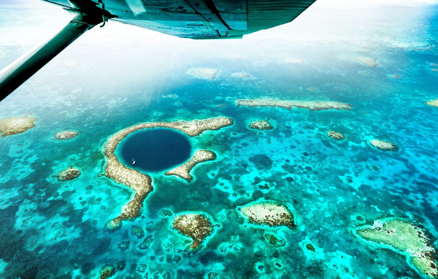 Vista panoramica aerea del Great Blue Hole - Dettaglio della barriera corallina del Belize da un'escursione in aereo - Voglia di viaggiare e concetto di viaggio con meraviglie della natura su filtro azzurro vivido