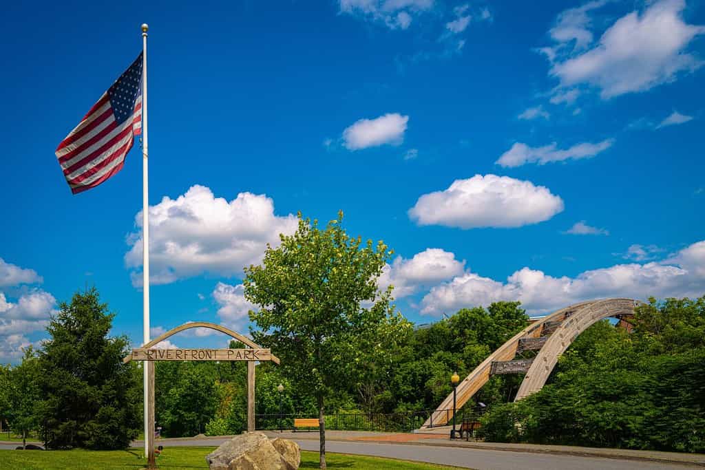 Houlton Riverfront Park nella contea di Aroostook, nel Maine settentrionale, in una giornata estiva con la bandiera americana che sventola nel vento e la vista del ponte ad arco Gateway Crossing