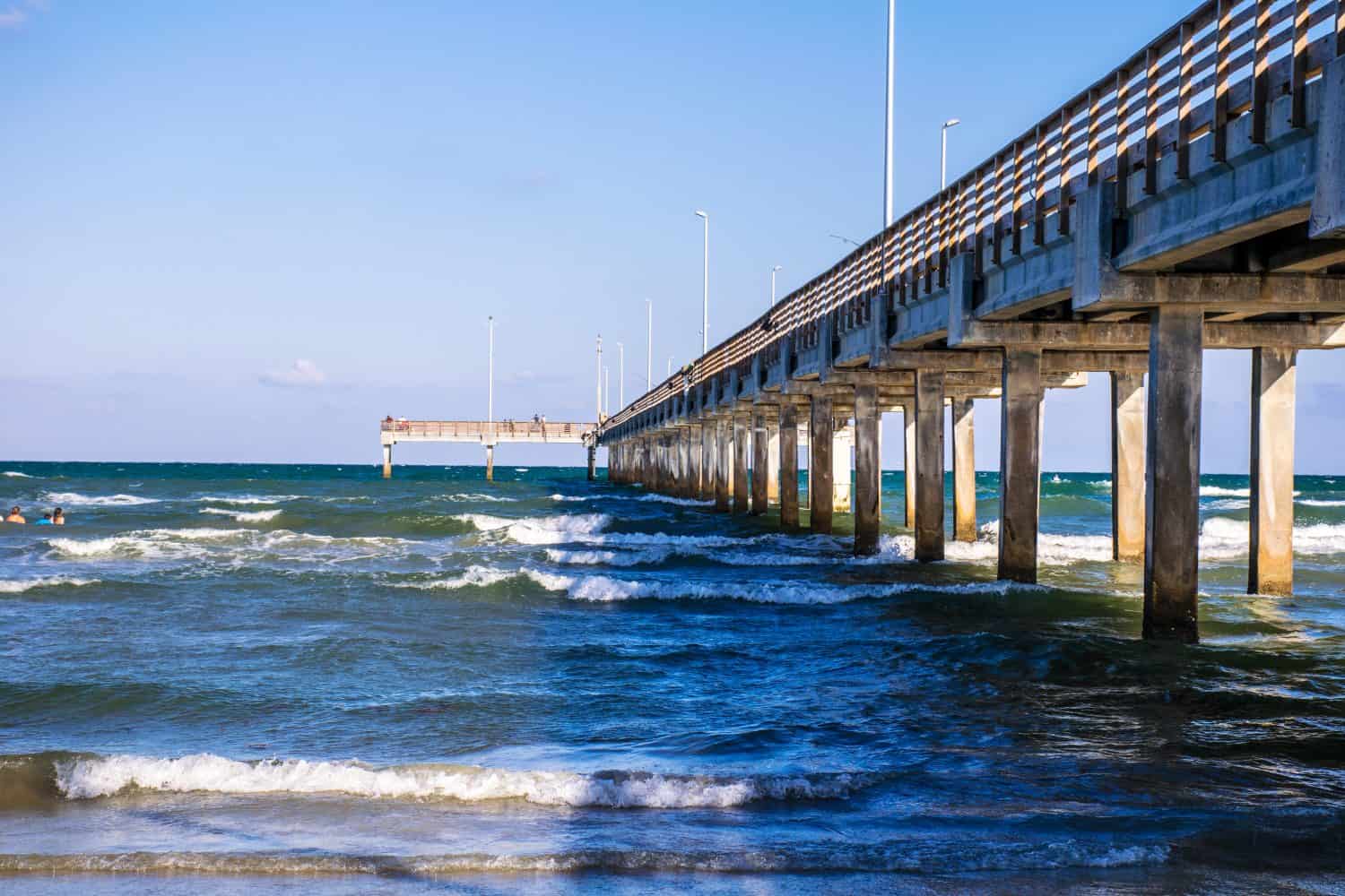 Lungo molo di pesca che si estende nel surf sulla spiaggia di Port Aransas lungo la costa nazionale di Padre Island Texas, un'isola barriera nel Golfo del Messico vicino a Corpus Christi, Texas, Stati Uniti