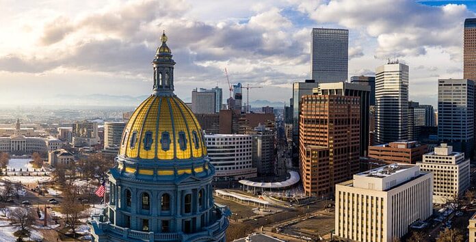 Colorado State Capitol Building e la città di Denver Colorado al tramonto.  Montagne Rocciose all'orizzonte