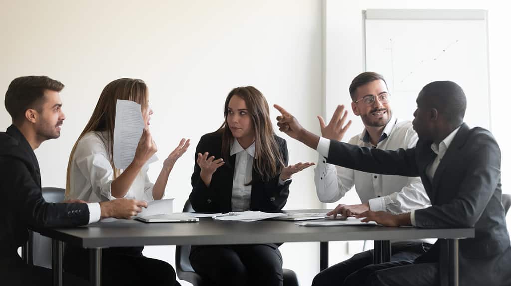 Dipendenti multietnici frustrati e pazzi siedono in una riunione d'ufficio, litigano, hanno una situazione lavorativa stressante, colleghi diversi e arrabbiati discutono sulla scartoffia, sulle statistiche finanziarie, sul concetto di stress lavorativo